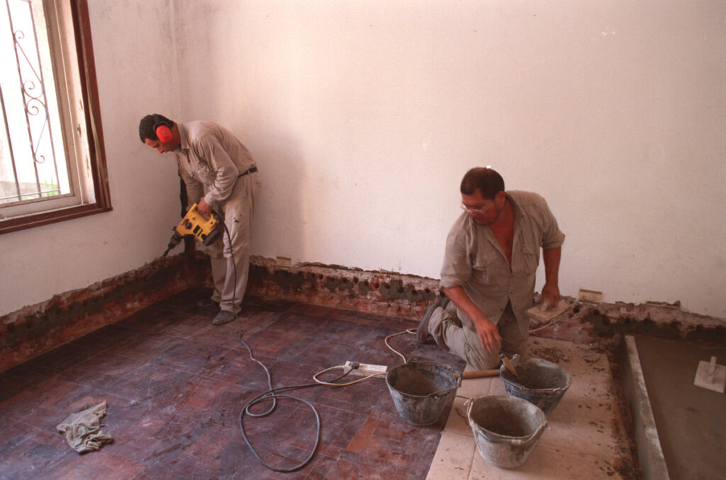 Paredes con humedad ascendente en la base del muro con manchas y pintura descascarada.