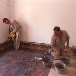 Paredes con humedad ascendente en la base del muro con manchas y pintura descascarada.